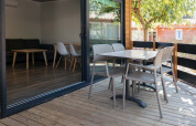 Houten terras bij Bungalow Quermany op Camping Mas Patoxas in Spanje, met buitenmeubilair en stoelen.