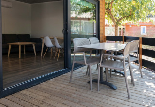 Veranda in legno del Bungalow Quermany al Camping Mas Patoxas, Spagna, con tavolo e sedie all’aperto.