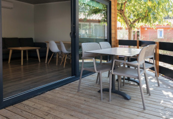 Wooden deck terrace of Bungalow Quermany at Camping Mas Patoxas, Spain, with table and chairs outside.