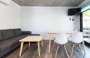 Modern living area in Bungalow Quermany at Camping Mas Patoxas, Spain, with sofa, dining table and wall TV.