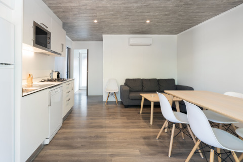 Interior moderno del Bungalow Quermany en Camping Mas Patoxas, España, con cocina, mesa y sofá.
