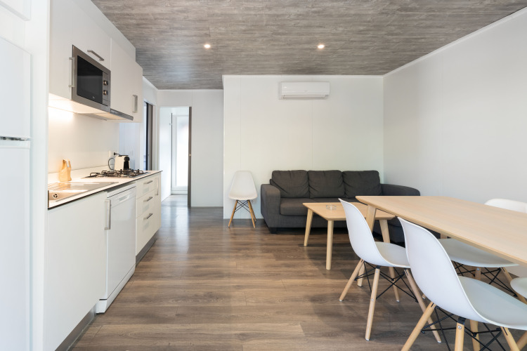 Moderne inrichting van Bungalow Quermany bij Camping Mas Patoxas, Spanje, met keuken, tafel en bank.