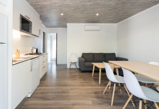 Interior moderno del Bungalow Quermany en Camping Mas Patoxas, España, con cocina, mesa y sofá.