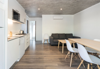 Interior moderno del Bungalow Quermany en Camping Mas Patoxas, España, con cocina, mesa y sofá.