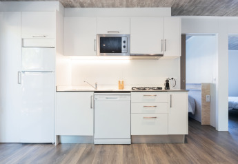 Modern kitchen in Bungalow Quermany at Camping Mas Patoxas in Spain, featuring white cabinets and wood flooring.