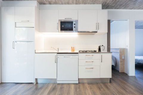 Cocina moderna en el Bungalow Quermany de Camping Mas Patoxas en España, con armarios blancos y suelo de madera.