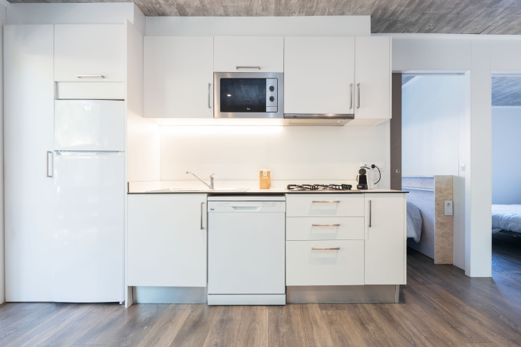 Moderne keuken in Bungalow Quermany op Camping Mas Patoxas in Spanje met witte kasten en houten vloer.