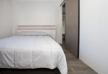 Camera da letto con letto matrimoniale e piumone grigio nel Bungalow Quermany al Camping Mas Patoxas in Spagna.