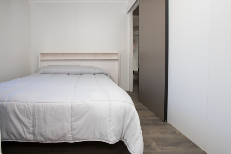 Bedroom with a double bed and gray comforter in Bungalow Quermany at Camping Mas Patoxas, Spain.