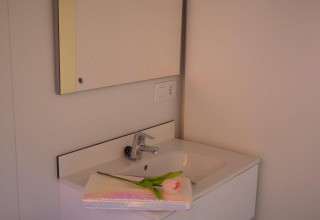 Baño moderno en el Bungalow Quermany, Camping Mas Patoxas, España, con lavabo blanco y espejo amplio.