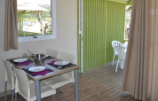 Indoor and outdoor dining area at Bungalow Morea, Camping Mas Patoxas, Spain, with a cozy modern setting.