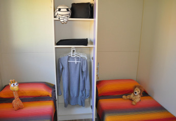 Twee bedden met kleurrijke dekens en knuffels in een kamer in Bungalow Morea bij Camping Mas Patoxas in Spanje.