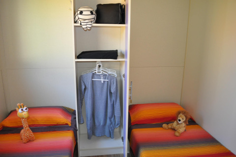Two beds with colorful covers and plush toys in a room at Bungalow Morea, Camping Mas Patoxas, Spain.
