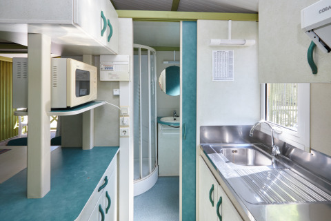 Moderne keuken en badkamer in Bungalow Morea op Camping Mas Patoxas, Spanje, met microgolfoven en gootsteen.