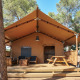 Tienda safari Glamping Tramuntana con terraza de madera, mesa de picnic y sillas bajo pinos.