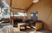 Zona lounge su terrazza in legno presso la tenda safari Glamping Tramuntana, Camping Mas Patoxas, Spagna.