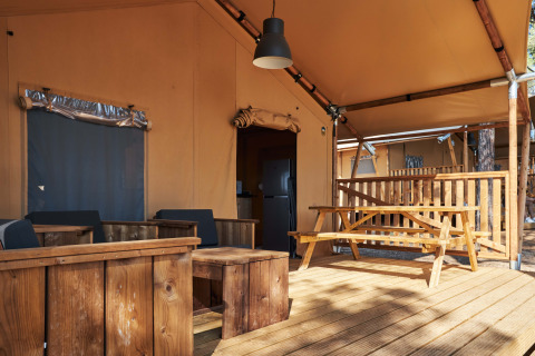 Outdoor terrace of a Glamping Tramuntana safari tent at Camping Mas Patoxas in Spain with wooden furniture.