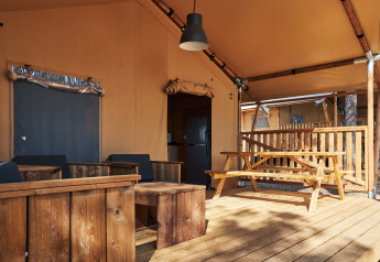 Outdoor terrace of a Glamping Tramuntana safari tent at Camping Mas Patoxas in Spain with wooden furniture.