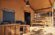 Terraza exterior del safari tent Glamping Tramuntana en Camping Mas Patoxas, España, con muebles de madera.