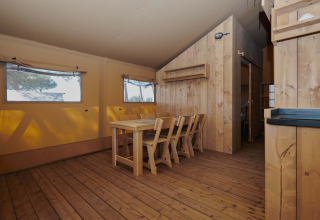 Vista interior de la tienda safari Glamping Tramuntana con muebles de madera en Camping Mas Patoxas, España.