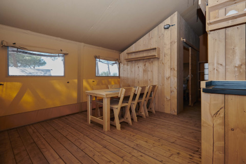 Vista interna della tenda safari Glamping Tramuntana con mobili in legno al Camping Mas Patoxas in Spagna.