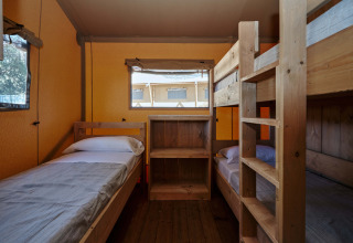 Interieur van een safaritent met eenpersoonsbed en stapelbedden bij Glamping Tramuntana, Spanje.