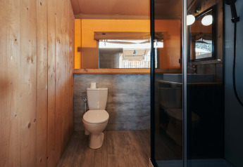 Badeværelse med trævægge, toilet og bruser i et luksustelt på Glamping Tramuntana, Camping Mas Patoxas.