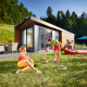 Twee mensen genieten van een barbecue bij een modern Panorama Chalet, omgeven door groene natuur.