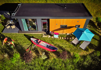 Panoramisch zicht op Panorama Chalets met terras, kajak, ligstoelen en parasol tussen het groen.