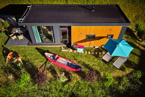 Luftfoto af Panorama Chalets med terrasse, kajak, solsenge og parasol, omgivet af grønt landskab.