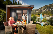 Dos personas desayunan al aire libre en un Panorama Chalet rodeado de montañas y ambiente acogedor.