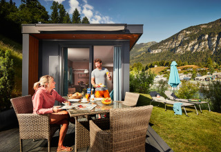 Dos personas desayunan al aire libre en un Panorama Chalet rodeado de montañas y ambiente acogedor.