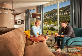 Una coppia si rilassa in un soggiorno moderno con vista sulle montagne nei Panorama Chalets.