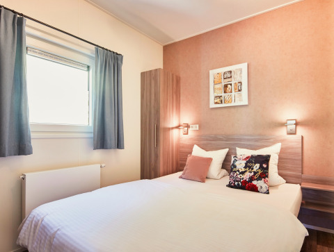 Dormitorio luminoso en Panorama Chalets con cama doble, decoración moderna y ventana grande.