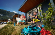 Pareja disfrutando bebidas afuera del tiny house Studio en Camping Seeblick Toni, Austria, con equipo de escalada.
