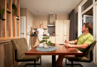 Twee mensen genieten van koffie in de lichte keuken van Studio tiny house op Camping Seeblick Toni, Oostenrijk.