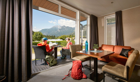 Twee mensen zitten buiten bij een tiny house Studio op Camping Seeblick Toni in Oostenrijk met berguitzicht.