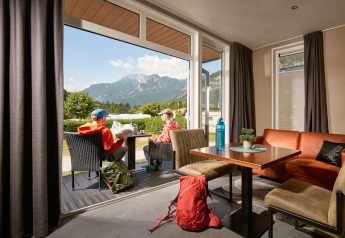 Twee mensen zitten buiten bij een tiny house Studio op Camping Seeblick Toni in Oostenrijk met berguitzicht.