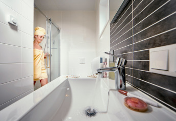 Woman steps out of shower in bathroom at Studio at Camping Seeblick Toni, Austria, dressed in a towel.