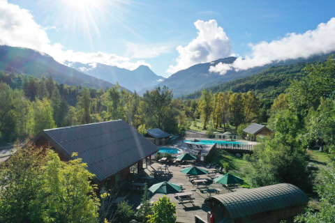 Parque vacacional con piscina, cabañas y vistas montañosas en Huttopia Vallouise, Provenza-Alpes-Costa Azul, Francia.