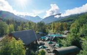 Billede af sommerhusområde med swimmingpool og bjerge i baggrunden ved Huttopia Vallouise, Provence-Alpes, Frankrig.