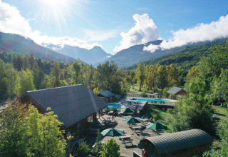 Parque vacacional con piscina, cabañas y vistas montañosas en Huttopia Vallouise, Provenza-Alpes-Costa Azul, Francia.