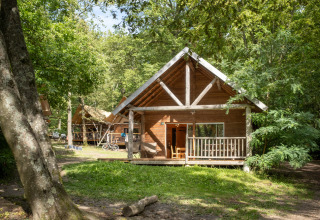 Knusse houten chalet omgeven door bos in vakantiepark Huttopia Versailles, Île de France, Frankrijk.