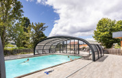 Outdoor swimming pool with glass cover and relaxing guests at Huttopia Versailles holiday park, Île de France.