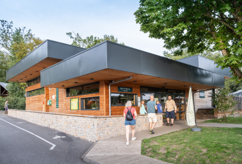 Visiteurs devant le bâtiment d'accueil en bois de Huttopia Versailles, Île-de-France, France.
