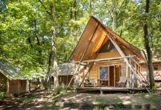 En træhytte med moderne design i en frodig skov ved Huttopia Versailles feriepark i Île de France, Frankrig.