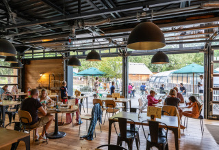 Gäste essen drinnen und draußen im Restaurant des Huttopia Versailles Ferienparks in Île-de-France, Frankreich.