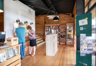 Two people explore the information area inside the Huttopia Versailles reception shop in Île de France.