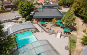 Luftfoto af Huttopia Versailles feriepark med overdækket swimmingpool, solterrasse og udendørs siddepladser.