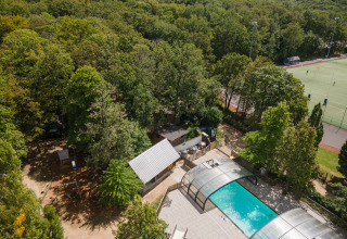 Luchtfoto van Huttopia Versailles vakantiepark met overdekt zwembad, bos en sportvelden in Île de France.